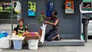 Dua pedagang menyiapkan bunga dagangannya di bilik telepon umum di samping jalan di Bangkok, Thailand (20/9). (AFP Photo/Jewel Samad)