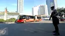 Bus Transjakarta melintas saat anggota kepolisian berjaga di kawasan Bundaran HI, Jakarta, Senin (1/5). Ratusan aparat kepolisian dikerahkan melakukan pengamanan demo buruh memperingati May day di sekitaran Bundaran HI. (Liputan6.com/Johan Tallo)