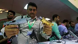 Seorang pengunjung membandingkan pistol saat Pameran Pertahanan Internasional dan Seminar "IDEAS 2016" di Karachi, Pakistan (23/11). Pameran alat tempur ini banyak diikuti oleh industri senjata dari berbagai negara. (Reuters/Akhtar Soomro)