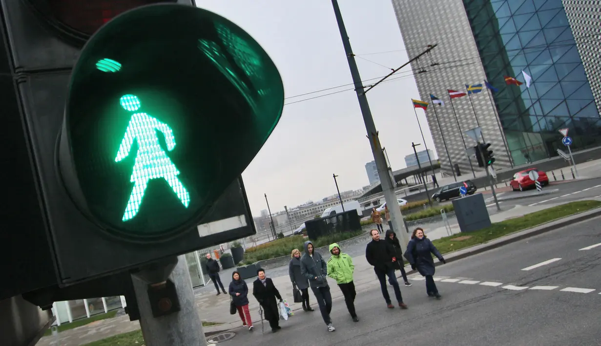 Orang-orang menyeberang jalan dengan lampu lalu lintas bergambar wanita di Vilnius, Lituania, Jumat (2/11). Hal itu untuk merayakan ulang tahun ke-100 wanita memperoleh pengakuan internasional dalam pemungutan suara di negara baltik. (Petras Malukas/AFP)