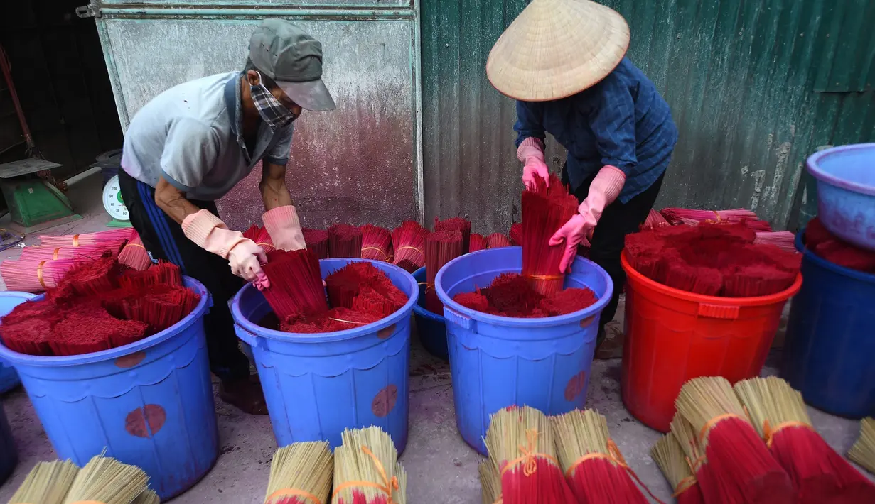 Para pekerja Vietnam mewarnai batang dupa di desa Quang Phu Cau, pinggiran Hanoi, Kamis (9/1/2020). Para penduduk desa sibuk menyiapkan ratusan ribu dupa untuk menyambut perayaan Tahun Baru Tet, Imlek versi Vietnam. (Manan VATSYAYANA/AFP)