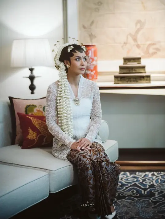 Adinia Wirasti jadi pengantin Jawa di momen pernikahannya. Kebaya pilihannya jatuh pada rancangan Kraton World. Modelnya klasik ala kebaya Kartini dengan bustier warna senada.  Adat Jawa semakin kental dengan sanggul yang besar berlapis ronce melati. Kemudian, terdapat cunduk mentul berjumlah ganjil. [Foto: IG/@venemapictures]