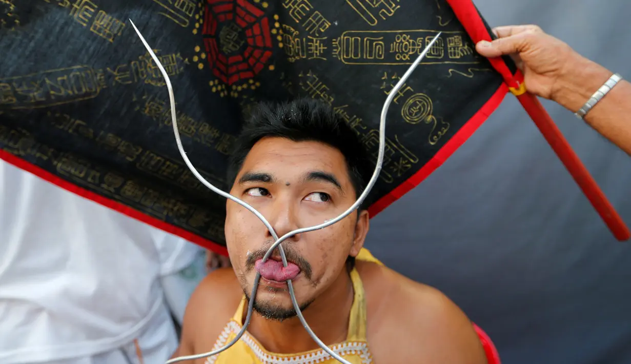 Seorang pemuja dari Kuil Samkong menusukkan besi pada lidahnya dalam Festival Vegetarian di Phuket, Thailand, Selasa (4/10). (REUTERS/Jorge Silva)