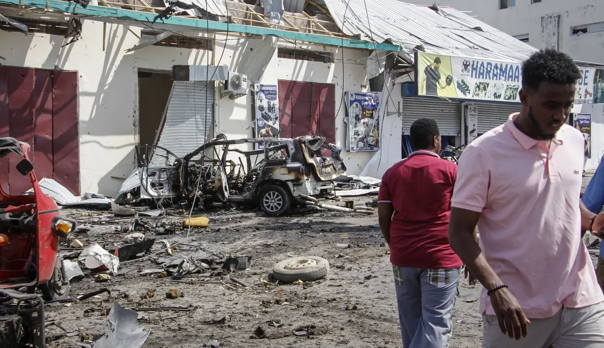 Orang-orang berjalan melewati reruntuhan di lokasi pemboman di Mogadishu, Somalia (13/2/2021). Bom kemudian meledak di pos pemeriksaan keamanan Markas Mejelis Nasional setelah ditembaki polisi.  (AP Photo/Farah Abdi Warsameh)