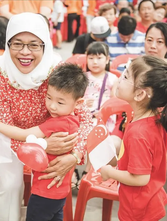 Halimah Yacob ketika memeluk seorang anak pada acara Hari Nasional di Singapura (10/8). (instagram.com/halimahyacob)