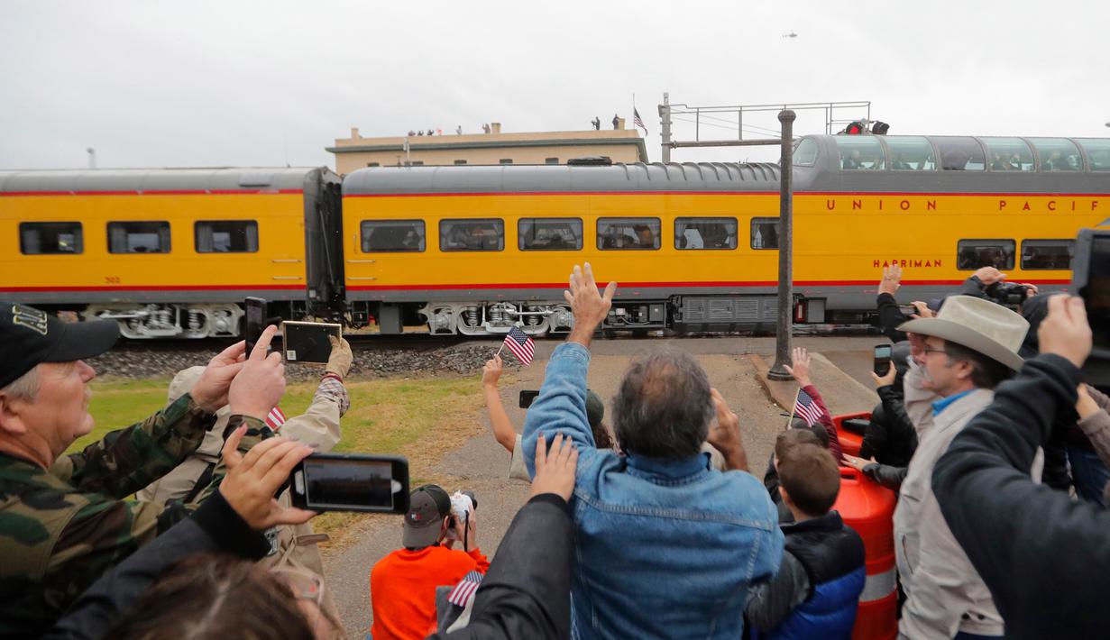 Warga memberi hormat saat kereta pembawa peti jenazah Presiden ke-41 AS George HW Bush melintasi Navasota, Texas, Kamis (6/12). Kereta pembawa jenazah presiden ke-41 AS itu ditarik oleh lokomotif yang didesain khusus. (AP Photo/Gerald Herbert)