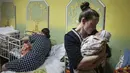 Kateryna Suharokova menggendong putranya yang baru lahir Makar di ruang bawah tanah rumah sakit bersalin yang diubah menjadi bangsal medis dan digunakan sebagai shelter bom di Mariupol, Ukraina, Senin (28/2/2022). Bayi itu lahir di tengah invasi militer Rusia ke Ukraina. (AP Photo/Evgeniy Maloletka)