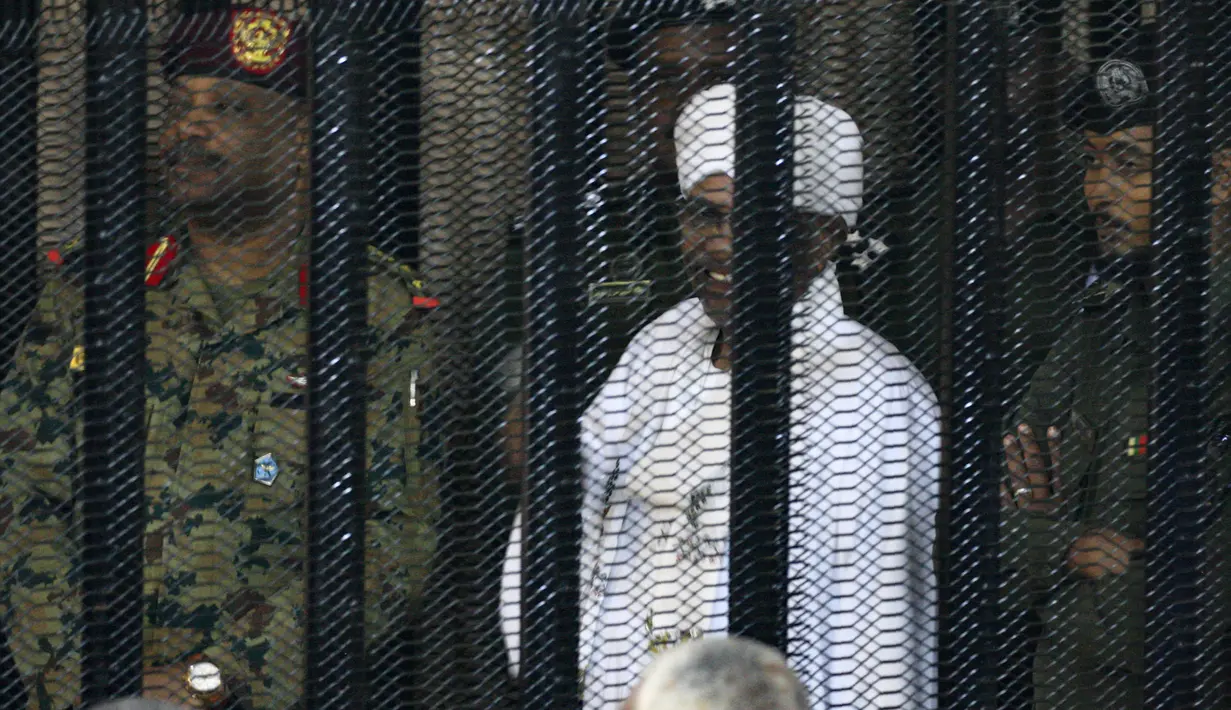 Presiden terguling Sudan, Omar al-Bashir ditempatkan di kandang terdakwa selama menjalani persidangan atas dakwaan korupsi di pengadilan di Khartoum, Senin (19/8/2019). Bashir  didakwa dengan tuduhan korupsi, kepemilikan mata uang asing dan menerima gratifikasi. (Ebrahim HAMID / AFP)