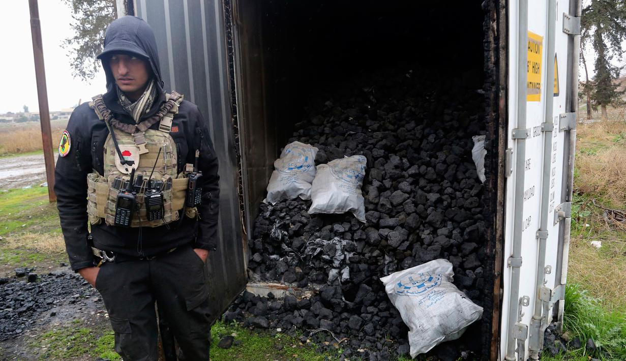 Seorang pasukan khusus Irak berdiri dekat kontainer berisi gas mustard yang ditemukan di sebuah gudang senjata di sisi timur Mosul, Sabtu (28/1). Pihak berwenang mengatakan bahwa gudang senjata itu milik kelompok militan ISIS. (AP Photo/Khalid Mohammed)