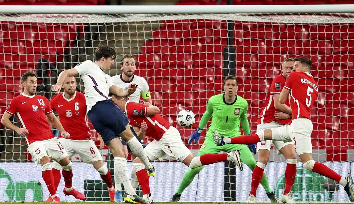 Bek Inggris, Harry Maguire (tengah) melepaskan tendangan yang berbuah gol kedua Inggris ke gawang Polandia dalam laga lanjutan Kualifikasi Piala Dunia 2022 Zona Eropa Grup I di Wembley Stadium, London, Rabu (31/3/2021). Inggris menang 2-1 atas Polandia. (AP/Andy Rain)