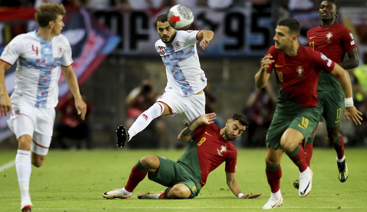 Gelandang Timnas Portugal, Bruno Fernandes (bawah) berusaha menghadang laju gelandang Luksemburg, Danel Sinani pada laga Grup J Kualifikasi Euro 2024 di Estadio Algarve, Selasa (12/9/2023) dini hari WIB. (AP Photo/Joao Matos)