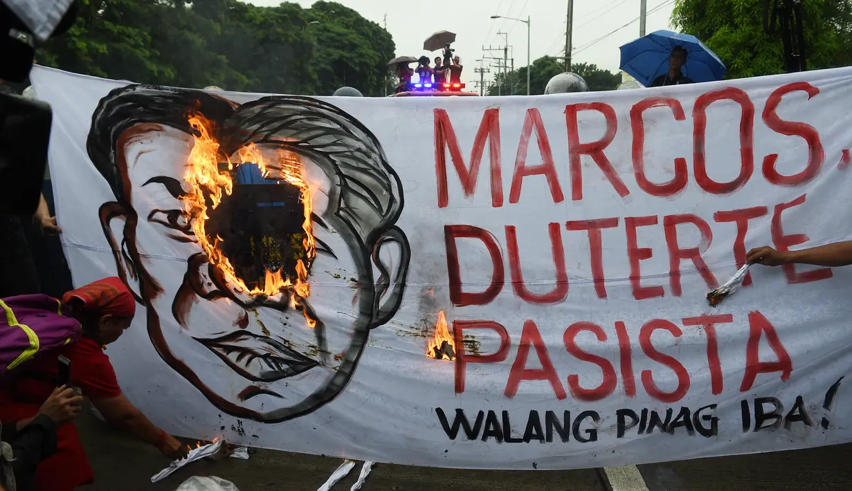 Demonstran membakar spanduk yang bergambar wajah Ferdinand Marcos dan Presiden Rodrigo Duterte saat ulang tahun Ferdinand Marcos ke-100 di Manila (11/9). (AFP Photo/Ted Aljibe)