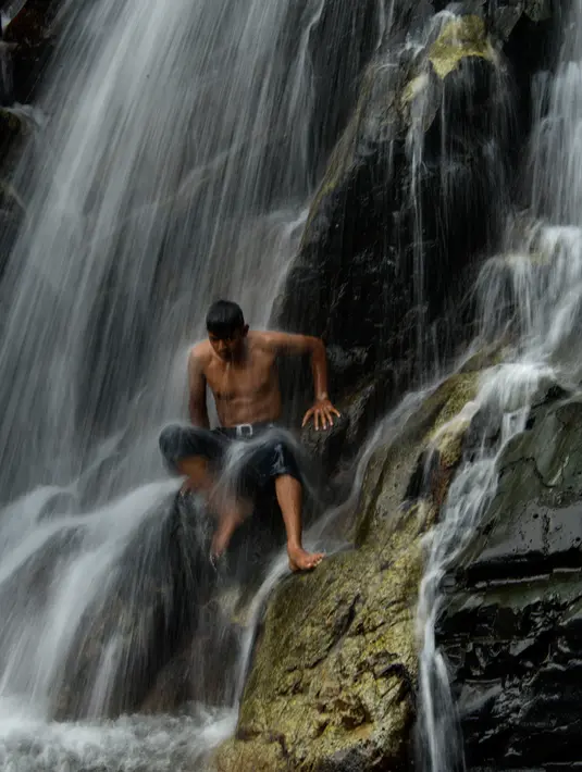 Seorang pemuda mendinginkan diri di air terjun di Samadua, Provinsi Aceh pada 9 Juli 2020. Aceh punya banyak destinasi wisata alam mempesona yang patut dikunjungi. (Photo by CHAIDEER MAHYUDDIN / AFP)