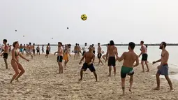 Orang-orang bermain sepak bola di pantai di kota pesisir Israel Tel Aviv (19/4/2021). Dengan lebih dari setengah populasi divaksinasi penuh dalam salah satu kampanye inokulasi COVID-19 tercepat di dunia. (AFP/menahem kahana)