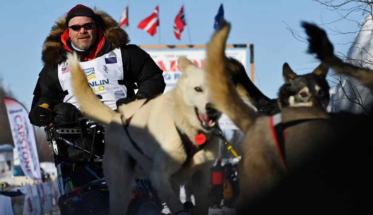 Aaron Burmeister dan timnya meninggalkan garis start Iditarod Sled Dog Race di Deshka Landing di Willow, Alaska, Minggu (7/3/2021). Tim anjing yang dipimpin oleh para pengemudi yang dikenal sebagai mushers berlari melintasi jalan-jalan bersalju. (Marc Lester/Anchorage Daily News via AP)