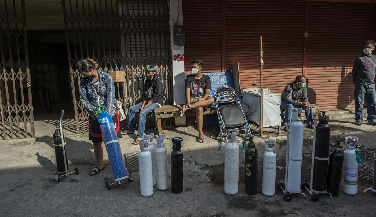 Antrean warga untuk mengisi ulang tabung oksigen di stasiun pengisian di kota Surabaya, Kamis (15/7/2021). Antrean yang terjadi di agen pengisian ulang oksigen itu disebabkan meningkatnya permintaan kebutuhan oleh warga. (Juni Kriswanto / AFP)