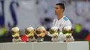 Bintang Real Madrid, Cristiano Ronaldo berpose dengan kelima trofi Ballon d'Or sebelum laga Real Madrid vs Sevilla di Stadion Santiago Bernabeu, Sabtu (9/12). Ronaldo baru saja meraih trofi kelima penghargaan Ballon d'Or 2017 di Paris. (AP/Francisco Seco)