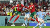 Pemain Maroko,&nbsp;Youssef En-Nesyri (kiri) dan Nayef Aguerd berduel udara dengan pemain&nbsp;Spanyol, Sergio Busquets saat laga 16 besar Piala Dunia 2022 yang berlangsung di Education City Stadium, Selasa (06/12/2022). (AP/Julio Cortez)