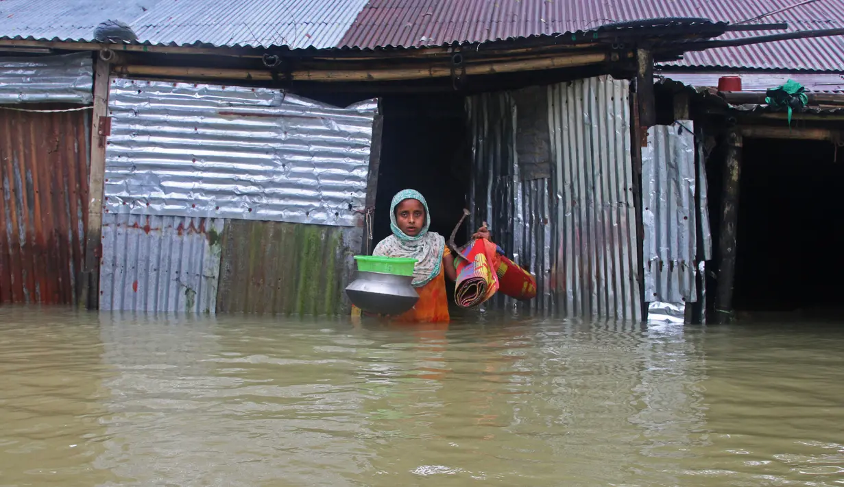 Seorang wanita membawa peralatan rumah tangga saat meninggalkan rumahnya yang terendam banjir di Sunamganj, Bangladesh, Minggu (12/7/2020). Banjir di sejumlah wilayah Bangladesh telah memengaruhi kehidupan lebih dari 1,3 juta orang dan mengakibatkan puluhan ribu keluarga mengungsi. (Xinhua)