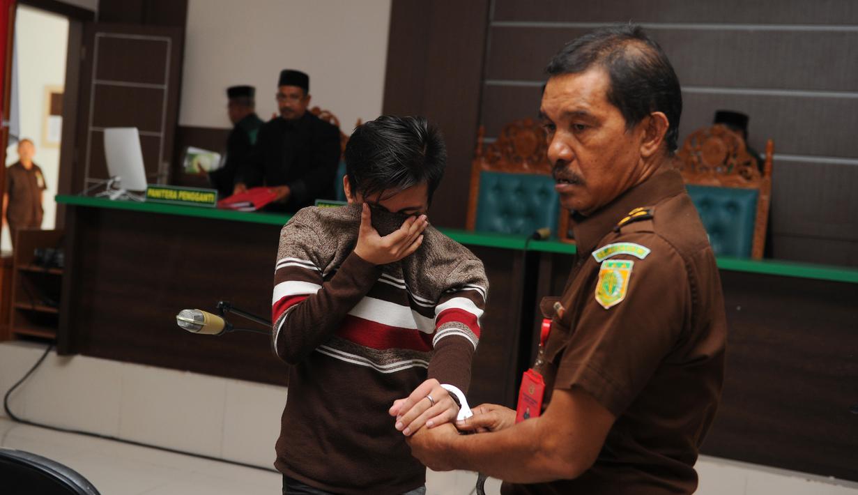 Terdakwa pasangan sejenis (gay) diborgol usai menjalani sidang di pengadilan syariah di Banda Aceh (17/5). Terdakwa dikenakan ancaman 100 kali cambuk atau denda 1.000 gram emas murni, atau 100 bulan penjara. (AFP/Chaideer Mahyuddin)