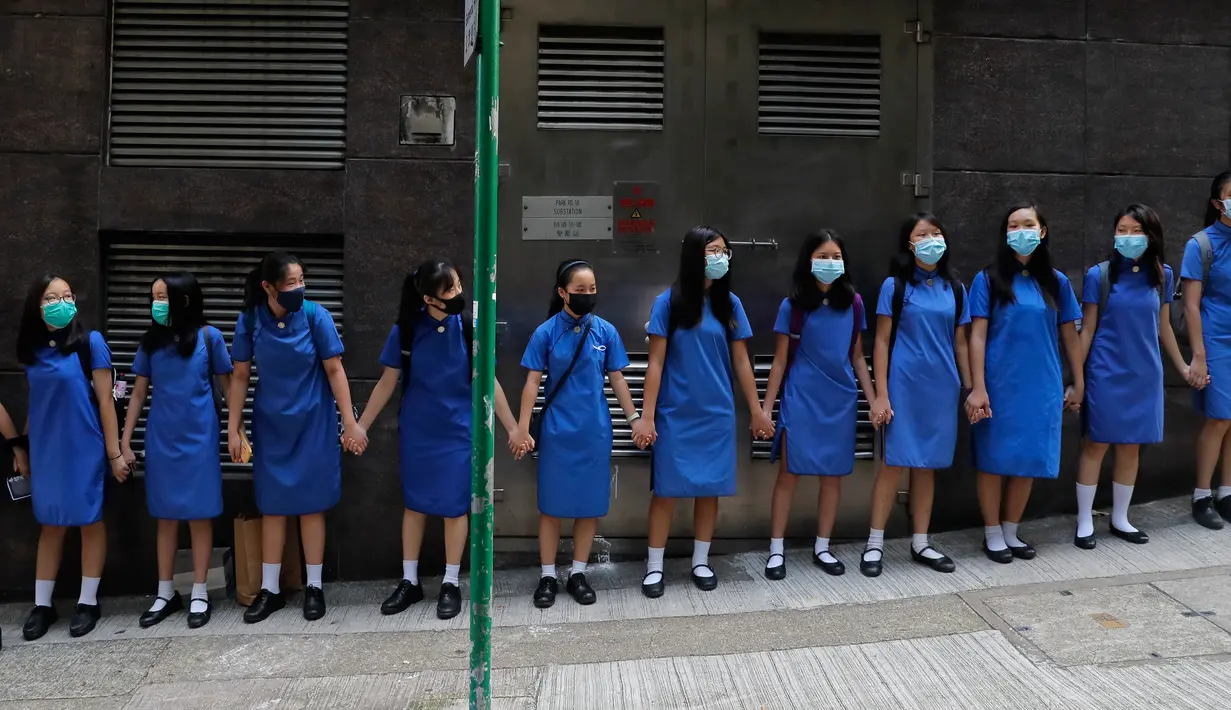 Para siswa dengan memakai masker saling memegang tangan mengelilingi St Stephen's Girls College di Hong Kong, Senin (9/9/2019). Aksi dilakukan para siswa yang masih berseragam sekolah sebagai bentuk dukungan terhadap demonstran anti pemerintah setelah bentrokan pada akhir pekan lalu. (AP/Kin Cheung)