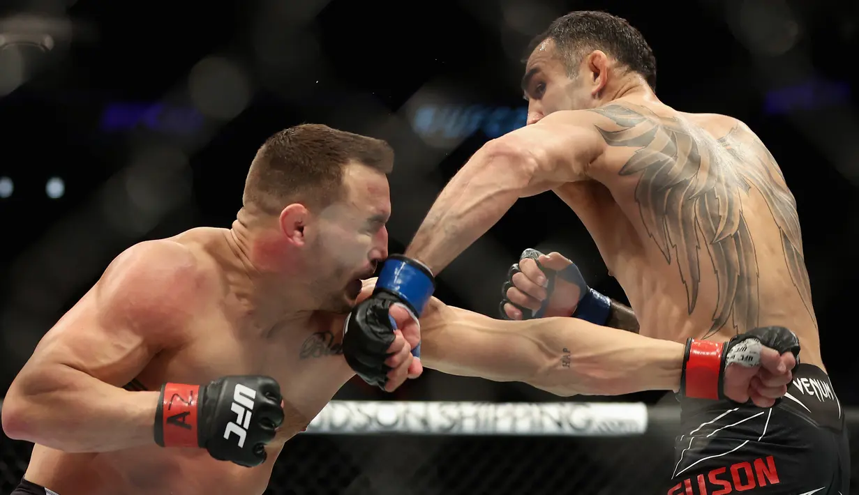 <p>Michael Chandler (kiri) melawan Tony Ferguson pada pertarungan kelas ringan putra UFC 274 di Footprint Center, Phoenix, Arizona, Amerika Serikat, 7 Mei 2022. Chandler dinyatakan menang KO atas Ferguson. (Christian Petersen/Getty Images/AFP)</p>