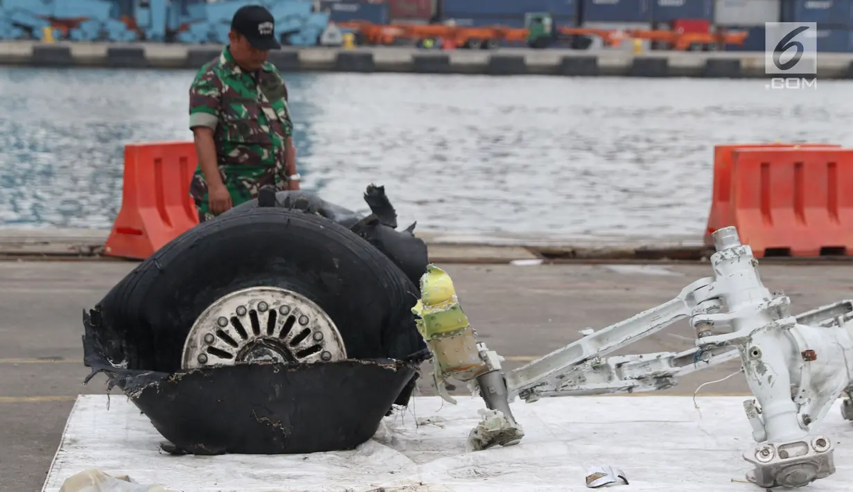 Petugas melihat-lihat bagian roda pesawat Lion Air PK-LQP JT 610 di Pelabuhan JICT 2, Jakarta, Senin (5/11). Bagian tersebut dipindah untuk dilakukan identifikasi dan pengecekan lebih lanjut oleh KNKT. (Liputan6.com/Helmi Fithriansyah)