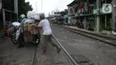 Penjaga perlintasan kereta api tanpa palang pintu, Wandi, membantu pengendara menyeberangi perlintasan di Kawasan Petamburan, Jakarta, Jumat (4/6/2021). Sudah 10 tahun, Bapak Wandi menjaga palang pintu perlintasan kereta api di kawasan tersebut. (merdeka.com/Imam Buhori)
