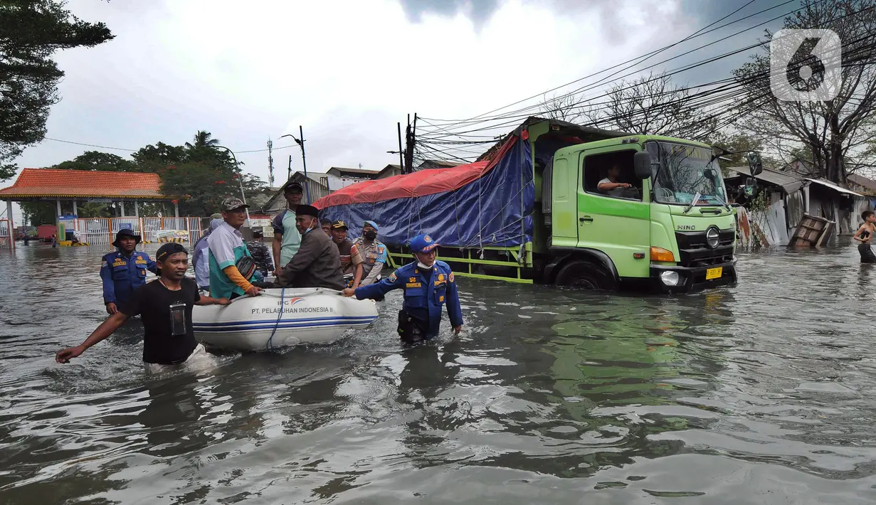 Petugas mengevakuasi warga dengan perahu karet saat banjir rob di kawasan Pelabuhan Sunda Kelapa, Jakarta, Selasa (7/12/2021). Banjir rob setinggi satu meter memutus Jalan Kerapu yang menghubungkan Ancol-Pluit. (merdeka.com/Arie Basuki)