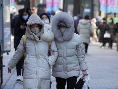 Para perempuan berjalan di jalan saat kondisi cuaca dingin di Seoul, Korea Selatan, Rabu (25/1/2023). Ribuan pelancong memadati bandara kecil di pulau Jeju Korea Selatan pada hari Rabu untuk mendapatkan penerbangan setelah penundaan karena kendala angin kencang dan salju tebal. (AP Photo/Ahn Young-joon)