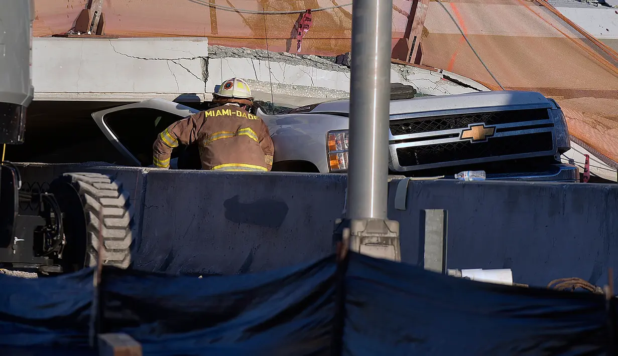 Seorang petugas pemadam kebakaran Miami-Dade Fire Rescue melihat sebuah truk pickup yang tertipa jembatan runtuh di Miami, Florida (15/3). Sedikitnya delapan mobil terjebak dalam reruntuhan jembatan. (Michael Laughlin / South Florida Sun-Sentinel via AP)