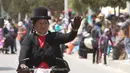 Seorang wanita melambaikan tangan saat mengikuti balapan sepeda Cholita di El Alto, La Paz, Bolivia (12/11). Pemenang dalam balapan ini berhak membawa pulang sepeda. (AP Photo / Juan Karita)