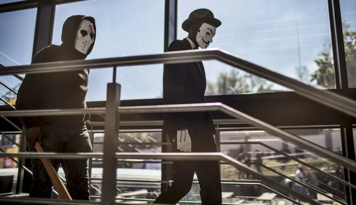 Dua cosplayer memakai topeng Anonymous dan Jason Voorhees berjalan saat menghadiri International Comic Con di Kyalami Race Course, Johannesburg, Afrika Selatan (14/9). (AFP Photo/Marco Longari)