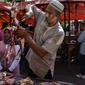 Pedagang memotong daging sapi dagangannya pada perayaan tradisi Meugang Ramadan 1440 Hijriah di Banda Aceh, 4 Mei 2019. Meugang merupakan tradisi turun temurun masyarakat Aceh dengan membeli, mengolah, hingga menyantap daging bersama keluarga. (CHAIDEER MAHYUDDIN/AFP)