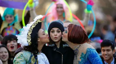 Aktris Mila Kunis (tengah) dicium oleh Amira Weeks (kiri) dan Jacques Berguig dalam sebuah parade di Cambridge (25/1). Mila Kunis dinobatkan sebagai "Woman of the Year" oleh kelompok teater Hasty Pudding. (AP Photo / Charles Krupa)