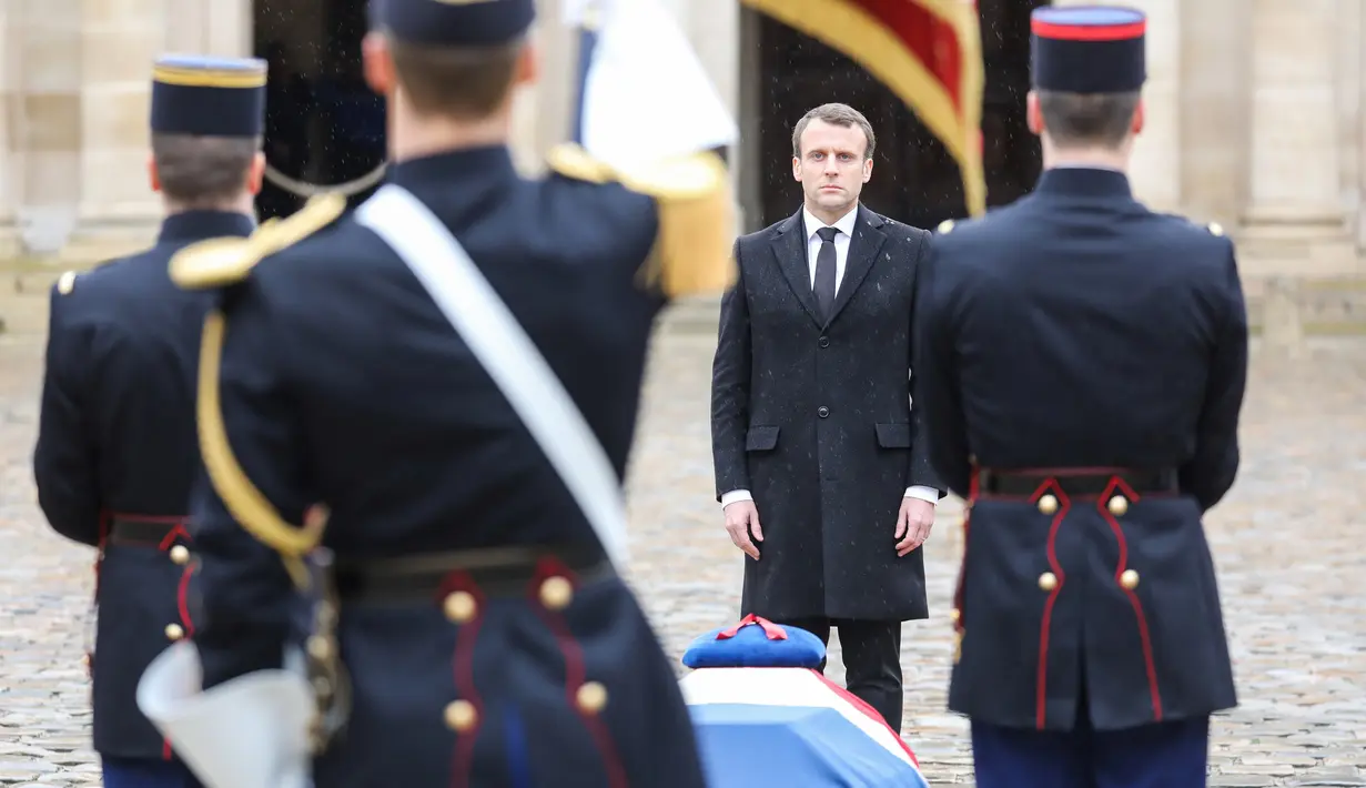 Presiden Prancis Emmanuel Macron  berdiri di dekat peti Letnan Kolonel Arnaud Beltrame dalam upacara nasional di Hotel des Invalides, Paris, Rabu (28/3). Macron memberikan penghargaan perwira tertinggi bagi Beltrame, Legiun d'Honneur. (AP/Christophe Ena)