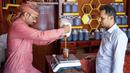 Seorang pedagang menuangkan madu ke dalam toples dilihat pelanggan di tokonya di Kota Taez, Yaman, 28 Juni 2022. Para ahli menganggap madu Yaman sebagai salah satu yang terbaik di dunia, termasuk Royal Sidr yang terkenal karena sifat terapeutiknya. (AHMAD AL-BASHA/AFP)