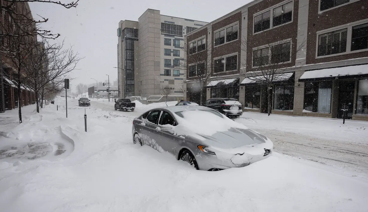 Sebuah mobil terkubur dalam salju selama badai salju di lingkungan East Village di Des Moines, Iowa, pada tanggal 12 Januari 2024. (Christian MONTERROSA/AFP)