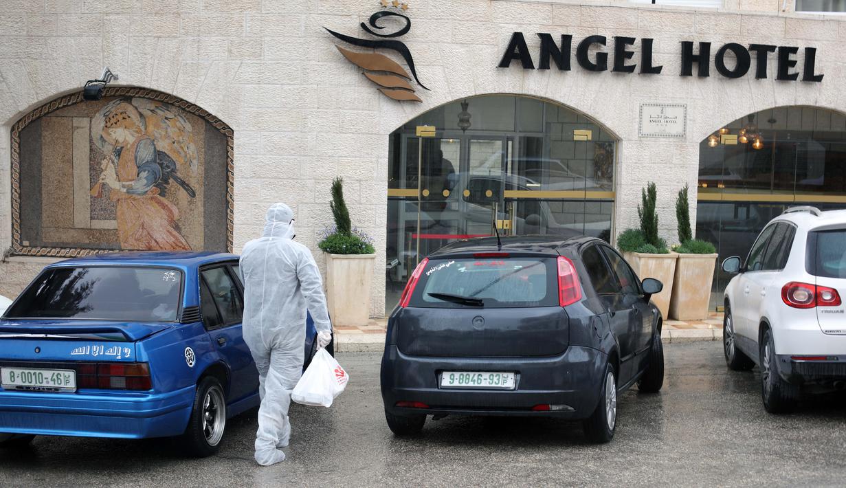 Seorang aparat kepolisian Palestina yang mengenakan pakaian pelindung terlihat di luar Angel Hotel di Kota Betlehem, Tepi Barat, pada 6 Maret 2020. Keadaan darurat mulai diberlakukan pada Jumat (6/3) di Palestina di tengah kekhawatiran penyebaran coronavirus baru. (Xinhua/Stringer)