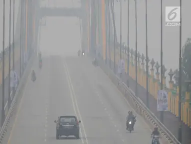 Sejumlah kendaraan melintas di atas jembatan yang diselimuti kabut asap di Kota Pekanbaru, Riau, Selasa (10/9/2019). Kabut asap akibat kebakaran hutan dan lahan (karhutla) tersebut menurunkan jarak pandang dan kualitas udara turun ke status tidak sehat. (Liputan6.com/Faizal Fanani)