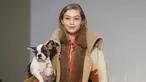 Model asal AS, Gigi Hadid menggendong anak anjing saat memamerkan rancangan Tod's di Milan Fashion Week, Milan, Italia, Jumat (23/2). (Filippo MONTEFORTE/AFP)