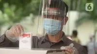 Petugas memakai face shield memasukan surat pemungutan suara dalam pemilihan serentak 2020 saat simulasi di Halam Kantor KPU, Jakarta, Rabu (22/7/2020). Simulasi pemungutan suara di TPS dengan menerapkan protokol kesehatan Covid-19. (merdeka.com/Imam Buhori)