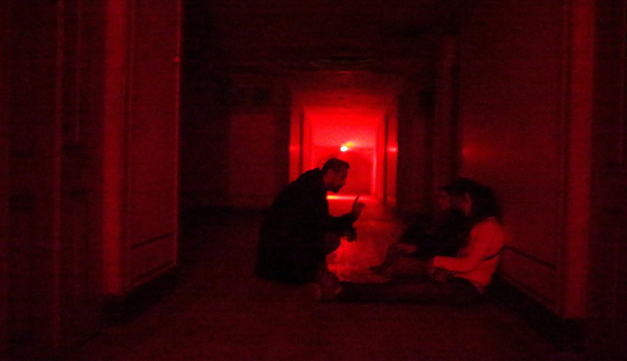 Pengunjung mendengarkan instruksi saat berada di dalam rumah hantu Quinta Nova da Assuncao di Belas, Portugal (13/5). Rumah hantu ini berisi 25 kamar dipenuhi penampakan bayangan dan suara dari pintu yang menutup secara acak. (REUTERS/Rafael Marchante)