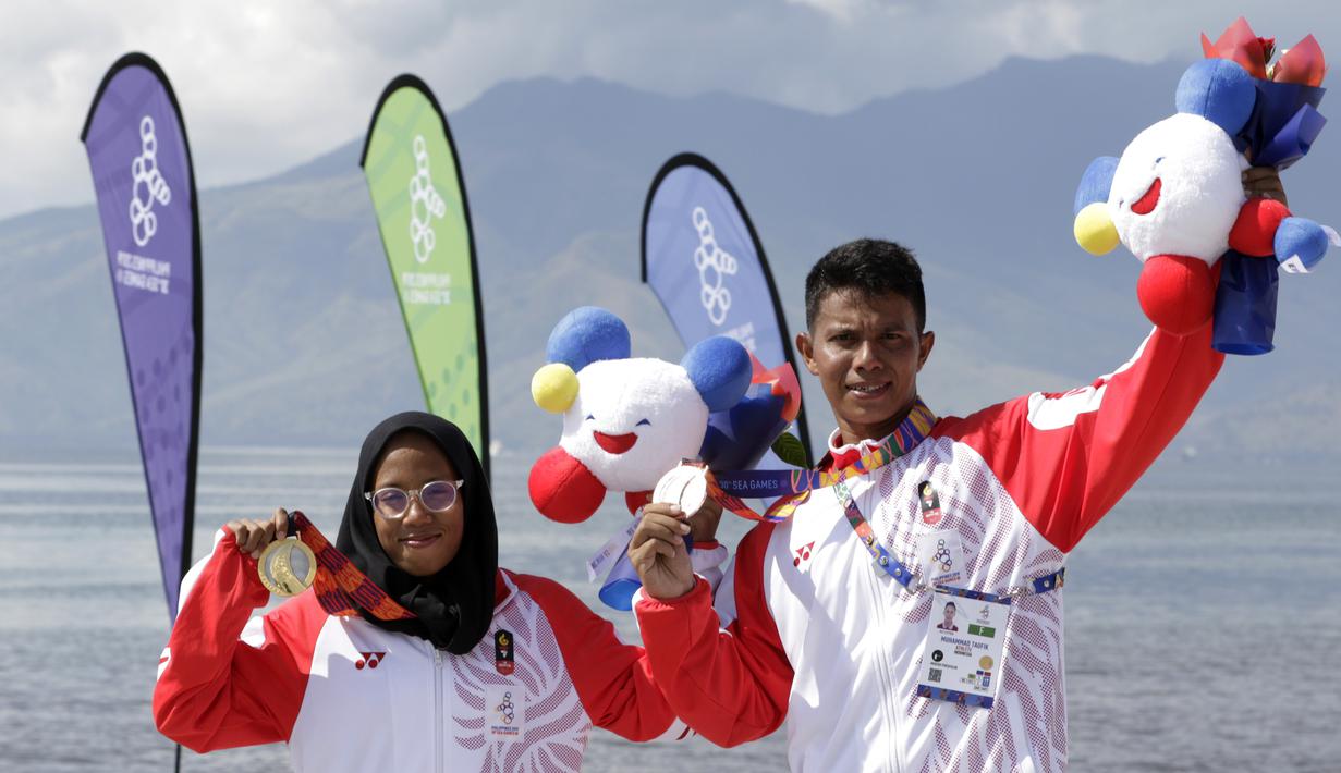 Atlet modern pentathlon, Muhammad Taufik dan Dea Salsabila, berpose usai meraih medali pada nomor beach triathle individual SEA Games 2019 di Subic, Jumat (6/12). Taufik meraih perunggu dan Dea meraih emas. (Bola.com/M Iqbal Ichsan)