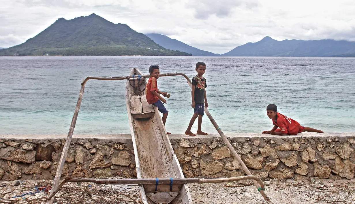 Anak-anak bersantai sejenak ditepi pantai sebelum bermain sepak bola di Alor, Nusa Tenggara Timur. (Bola.com/Nicklas Hanoatubun)