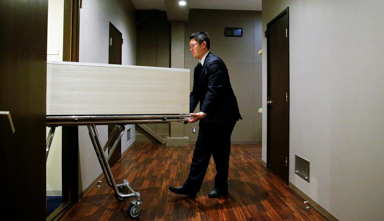 Petugas memindahkan peti jenazah ke sebuah kamar di 'Corpse Hotel', Kawasaki, Jepang, 20 April 2016. Dengan tarif setara Rp 1,1 juta, konsumen dapat menyimpan jenazah kerabatnya untuk periode 4 hari, sebelum dikirim ke krematorium. (REUTERS/Thomas Peter)