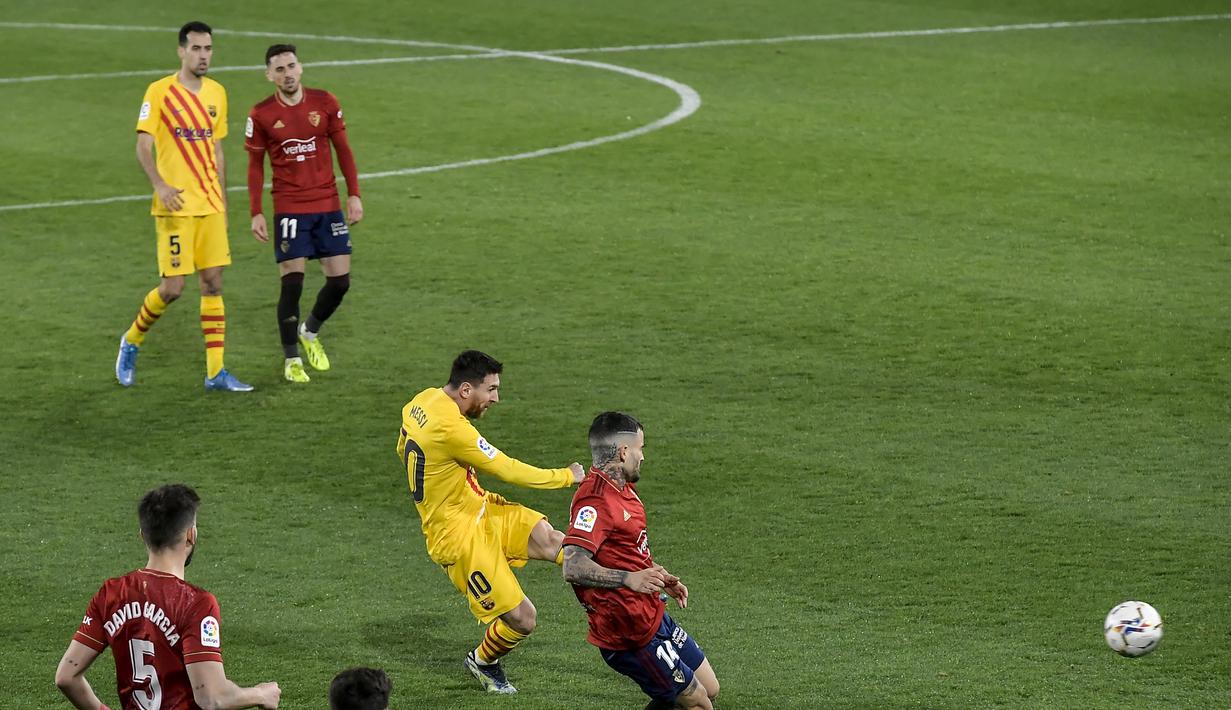 Penyerang Barcelona, Lionel Messi (tengah) melakukan tembakan ke gawang Osasuna pada pertandingan lanjutan La Liga Spanyol di stadion El Sadar di Pamplona, Spanyol, Minggu (7/3/2021). Barcelona kini berjarak tiga poin dari Real Madrid yang ada di peringkat ketiga. (AP Photo/Alvaro Barrientos)