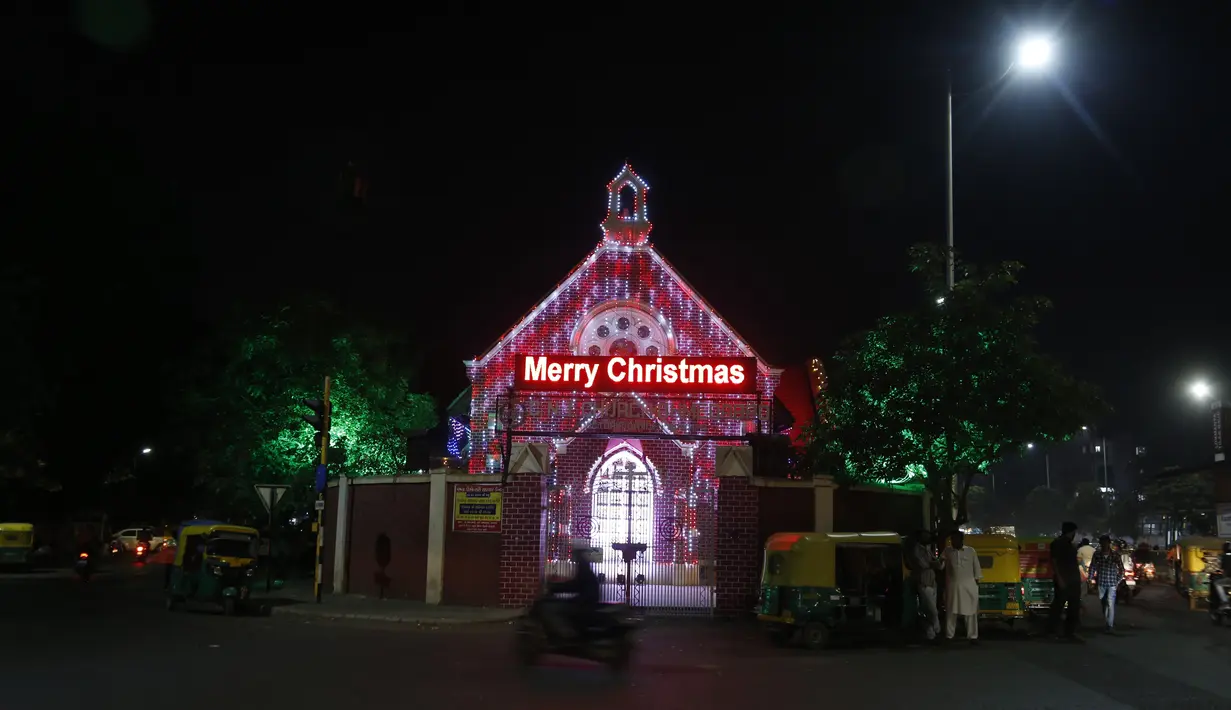 Seorang pengendara skuter melewati Gereja yang diterangi lampu pada malam Natal di Ahmedabad, India, Jumat (24/12/2021). (AP Photo/Ajit Solanki)