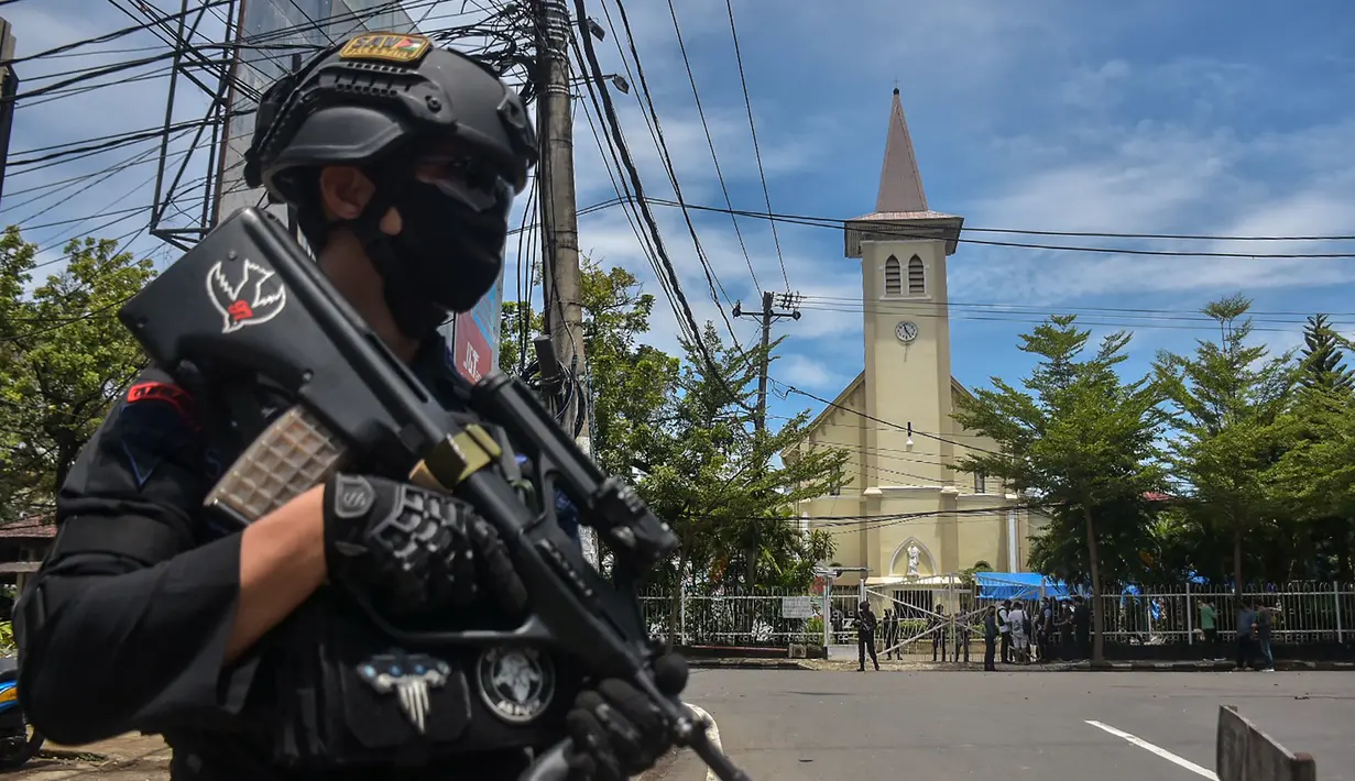 Polisi berjaga di luar gereja setelah ledakan di Makassar (28/3/2021). Berdasarkan informasi yang dihimpun di lokasi, garis polisi pun telah dibentangkan oleh petugas. Petugas masih bersiaga mengamankan lokasi. (AFP/Indra Abriyanto)