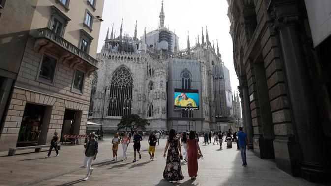 Pejalan kaki melewati layar di katedral Duomo yang menunjukkan model Moschino selama Milan Digital Fashion Week, di Milan, Italia, 14 Juli 2020. Empat puluh rumah mode menampilkan koleksi pakaian untuk musim semi/musim panas 2020 dalam format digital di tengah pandemi Covid-19. (AP Photo/Luca Bruno)